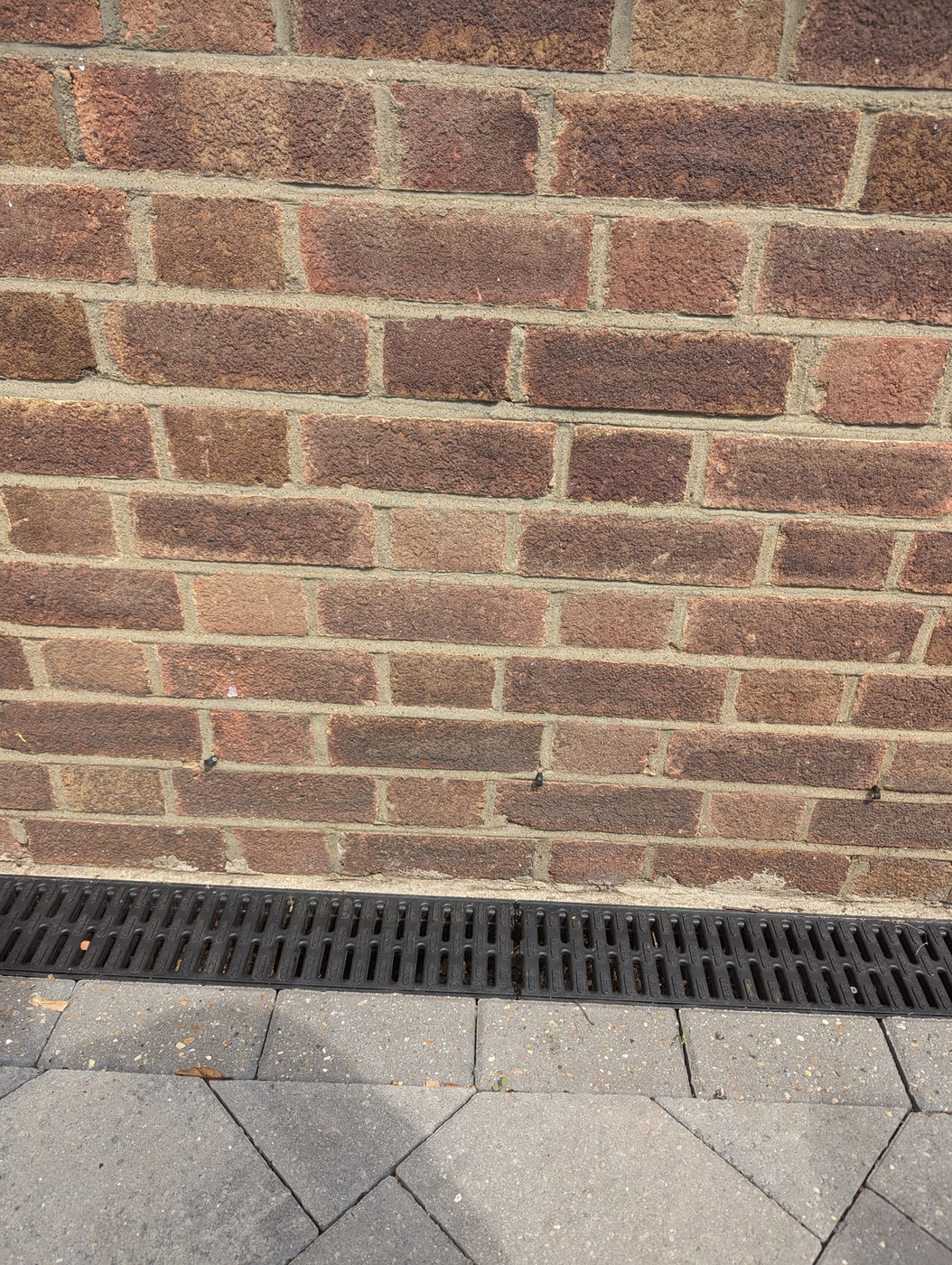New drainage channel installed along the base of a brick wall